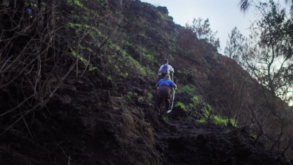 Hikers trekking Mount Batur before sunrise with headlamps on the volcanic trail, Kintamani, Bali